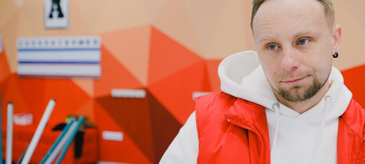Serious male curling player in sportswear looking away with pensive face while standing near brooms and score board during game